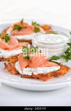 Frittelle croccanti di patate (una frittella, in particolare una di patate grattugiate) con salsa di formaggio cremoso con erbe e salmone Foto Stock