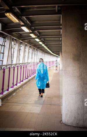 Una giovane signora tailandese fa la sua strada lungo una camminata in cielo verso un treno sopraelevato BTS a Bangkok, Thailandia. Foto Stock