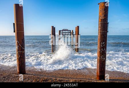 Brighton UK 6th ottobre 2022 - le onde rotolano dentro dal molo ovest di Brighton su una bella mattina soleggiata ma fredda: Accreditamento Simon Dack / Alamy Live News Foto Stock