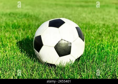 Palla da calcio classica, tipica in bianco e nero, posta sul punto del tappeto erboso dello stadio. Tradizionale palla di calcio sul campo di erba verde di ar Foto Stock