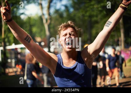 SÌ. Un ragazzo eccitato urlando i suoi polmoni fuori ad un festival di musica. Foto Stock