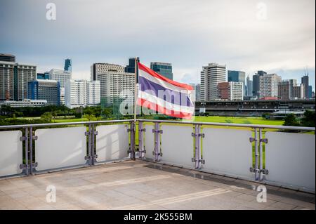 La bandiera della Thailandia vola sulla piattaforma della stazione di transito di massa del treno sopraelevato BTS di Ratchadamri, Bangkok, Thailandia. Foto Stock