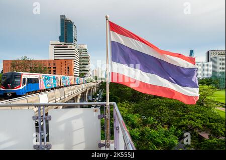 La bandiera della Thailandia vola sulla piattaforma della stazione di transito di massa del treno sopraelevato BTS di Ratchadamri, Bangkok, Thailandia. Foto Stock