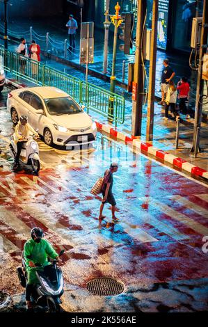 I pedoni attraversano il famoso incrocio di Asoke attraversando la zona pedonale in una notte molto piovosa a Bangkok in Thailandia. Foto Stock
