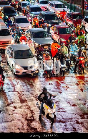 Il traffico attende alla traversata zebra presso la famosa e trafficata Asoke montri Rd. Incrocio stradale a Bangkok, Thailandia in una serata piovosa bagnata. Foto Stock