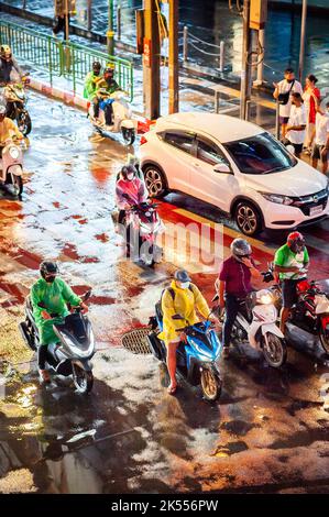 Il traffico attende alla traversata zebra presso la famosa e trafficata Asoke montri Rd. Incrocio stradale a Bangkok, Thailandia in una serata piovosa bagnata. Foto Stock