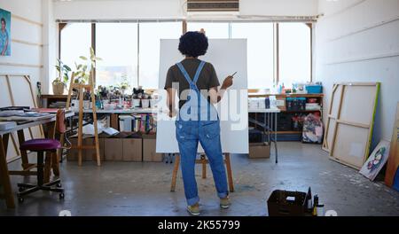 Donna artista nel suo studio, pittura arte, guardando la tela per ispirazione per dipingere nuovo progetto. Giovane pittore indiano creativo che lavora in lei Foto Stock