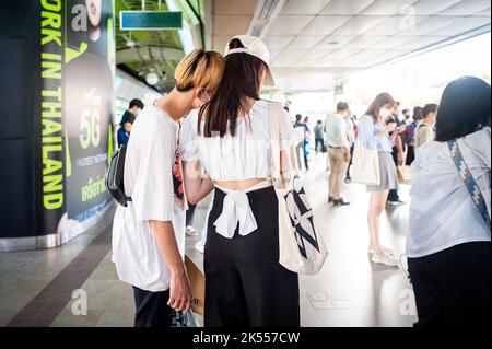 Una bella giovane coppia tailandese condividere un momento incantevole sulla piattaforma del Siam Sky train stazione, Bangkok, Thailandia. Foto Stock