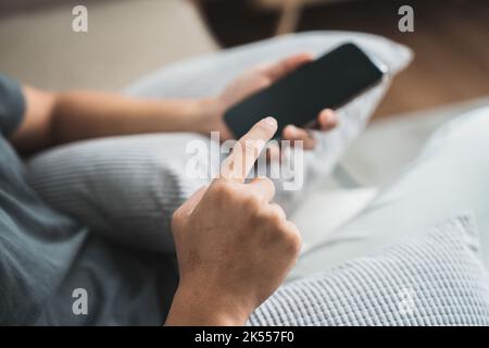 Giovane casual tenere e utilizzare lo smartphone per messaggi sms, uomo hipster digitando telefono cellulare touchscreen nel bar. Business, lifestyle, tecnologia e. Foto Stock