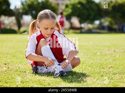 Sport, ragazza e giocatore di calcio con bambino in erba prima di gioco all'aperto e l'esercizio. Bambini, fitness e scarpe durante gli allenamenti di calcio, preparandosi Foto Stock