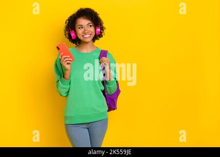 Ritratto di ragazza attraente sguardo occupato spazio brainstorm tenere zaino isolato su sfondo giallo Foto Stock