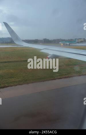 Guarda attraverso una finestra degli aeroplani su con la pioggia che corre attraverso il portale, per vedere la pista e la giornata umida all'esterno. Foto Stock