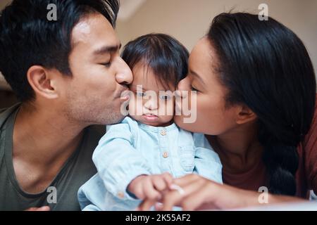 Amore, disabilità e sindrome di Down genitori bacio bisogni speciali capretto con apprezzamento. Mamma, papà e bambino disabili a casa di Puerto Rico con felice e. Foto Stock