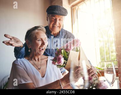Fiori a sorpresa, festa d'amore e coppia anziana con sorriso per celebrare il compleanno, l'anniversario o l'evento romantico nel ristorante. Uomo e donna Foto Stock