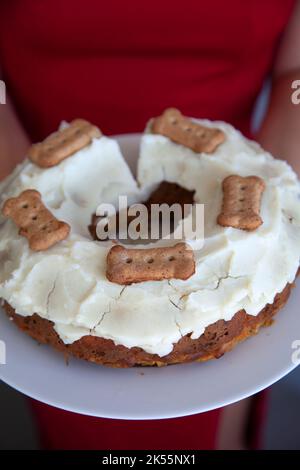 Donna che tiene burro di arachidi e torta di carote con patata e yogurt glassa per cane Foto Stock