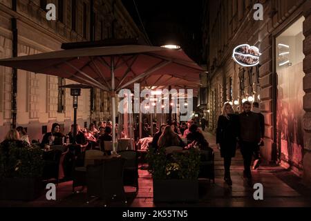 Foto della terrazza di un bar caffetteria e ristorante di Belgrado, Serbia affollata e piena di persone che godono del calore di un sistema di riscaldamento elettrico Foto Stock
