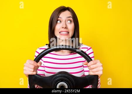 Foto di bella giovane donna tenere il volante fallito test di guida vestito alla moda a righe isolato su sfondo giallo Foto Stock