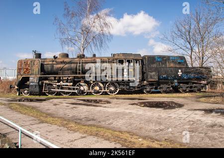 Una vecchia e fatiscente locomotiva a vapore del PKP in piedi su un lato in un giorno di autunno cupo. Foto Stock