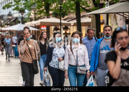 Immagine di una bianca gente caucasica che cammina, giovani e donne anziane, nelle strade di Belgrado, Serbia, indossando una maschera protettiva, durante il Foto Stock