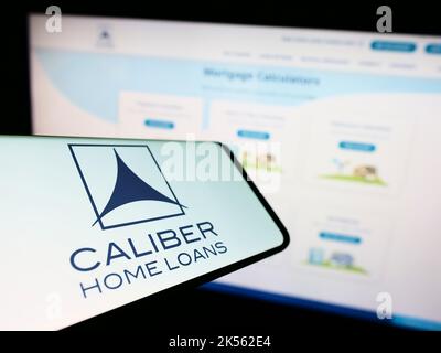 Telefono cellulare con il logo della società finanziaria statunitense Caliber Home Loans Inc. Sullo schermo di fronte al sito web. Messa a fuoco al centro a destra del display del telefono. Foto Stock