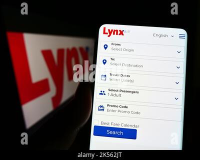 Persona che tiene il cellulare con il sito web della compagnia aerea canadese Lynx Air (1263343 Alberta Ltd.) sullo schermo con il logo. Messa a fuoco al centro del display del telefono. Foto Stock