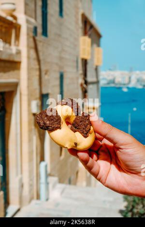 Primo piano di un uomo in possesso di un qaghaq tal-ghasel, noto anche come anello di miele in inglese, tipico di Malta, sulla strada nella città vecchia di la Valletta, Malta, Foto Stock