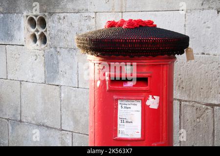 Un cappello di lana lavorato a maglia nera copre una scatola di colonne rosse. Commemorando la triste morte della Regina Elisabetta II, il più lungo monarca regnante della storia britannica. Foto Stock