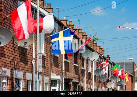 BELFAST, IRLANDA DEL NORD. 04 GIU 2016: Le case di Iris Drive a West Belfast sono decorate con le bandiere di tutti i 24 paesi che si sono qualificati per l'Euro 2016. I residenti hanno organizzato un sweepstake, con ogni casa che deve volare la bandiera del loro paese. Si ritiene che sia la prima volta che le bandiere dell'Inghilterra e dell'Irlanda del Nord sono volutamente volate in questa zona repubblicana di Belfast occidentale. Foto Stock