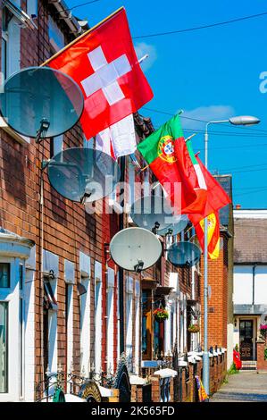 BELFAST, IRLANDA DEL NORD. 04 GIU 2016: Le case di Iris Drive a West Belfast sono decorate con le bandiere di tutti i 24 paesi che si sono qualificati per l'Euro 2016. I residenti hanno organizzato un sweepstake, con ogni casa che deve volare la bandiera del loro paese. Si ritiene che sia la prima volta che le bandiere dell'Inghilterra e dell'Irlanda del Nord sono volutamente volate in questa zona repubblicana di Belfast occidentale. Foto Stock