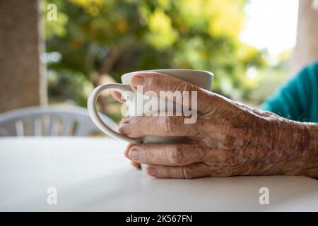 donna anziana che tiene una tazza Foto Stock