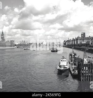 1950s, storico, una vista lungo il Tamigi, Londra, Inghilterra, Regno Unito, con il Palazzo di Westminster, casa delle due Case del Parlamento britannico sul lato sinistro e un molo con un lanciatore ormeggiato. Foto Stock