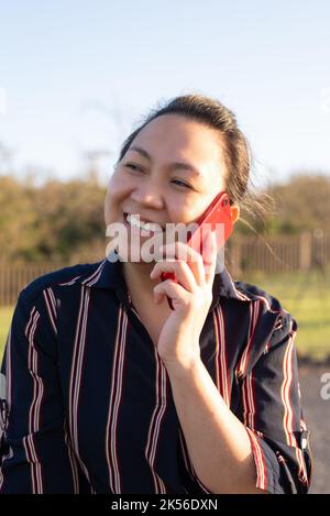 Una donna asiatica filippina parla al telefono al tramonto. Primo piano ritratto Foto Stock