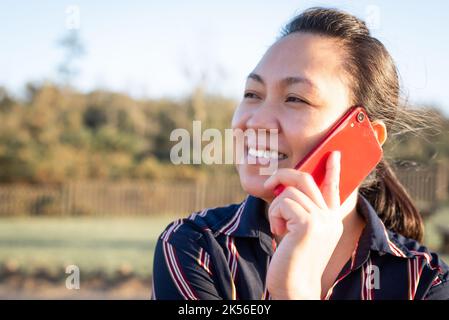 Una donna asiatica filippina parla al telefono al tramonto. Primo piano ritratto Foto Stock