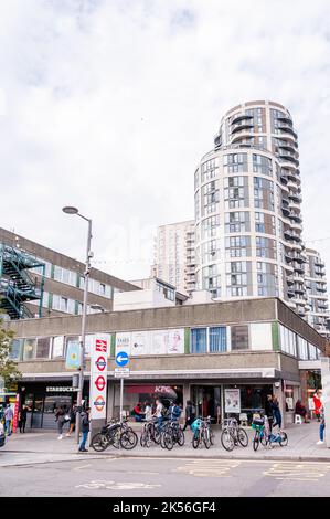 I pedoni passeranno accanto ai negozi indipendenti sulla Station Parade nel centro di Barking, con un alto e nuovo appartamento a Barking Foto Stock