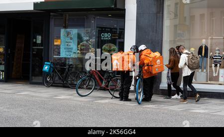 Ixelles, Regione capitale di Bruxelles - Belgio - 05 13 2021 - consegna di cibo al ristorante Mac Donalds Fastfood con biciclette arancioni Foto Stock