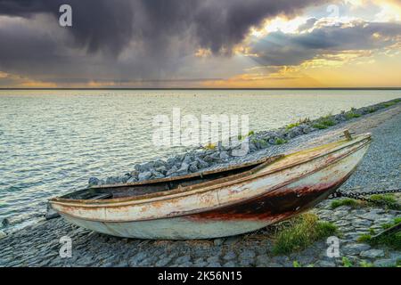 Barca a remi su scivolo con meccanismo di sollevamento lungo la diga Del Ijsselmeer con le nuvole di pioggia di colore rosso che scivola sopra il lago Foto Stock