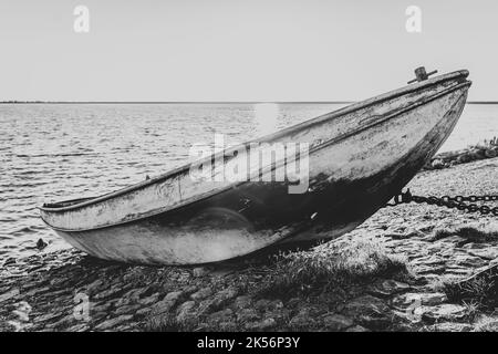 Barca a remi su scivolo con meccanismo di sollevamento lungo la diga Del Ijsselmeer con le nuvole di pioggia di colore rosso che scivola sopra il lago Foto Stock