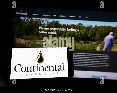 Persona che tiene il cellulare con il logo della società petrolifera statunitense Continental Resources Inc. Sullo schermo di fronte alla pagina web. Messa a fuoco sul display del telefono. Foto Stock