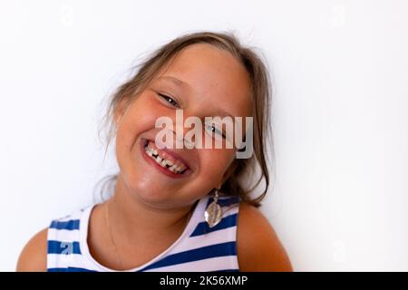 Felice ragazza bionda sorridente con bambino temporaneo latte denti accovacciati. Pratica ortodontica e lavoro dentale, cura Foto Stock