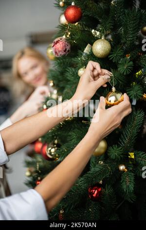 vista parziale di donna multirazziale decorazione albero di natale vicino a famiglia multietnica, immagine stock Foto Stock