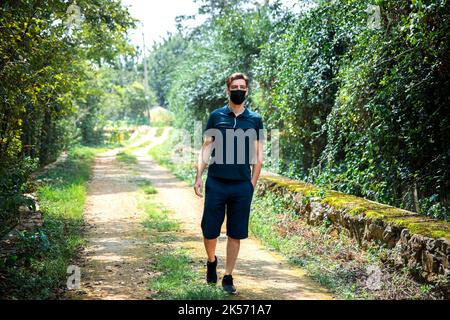 L'uomo che indossa la maschera cammina sulla strada del villaggio Foto Stock