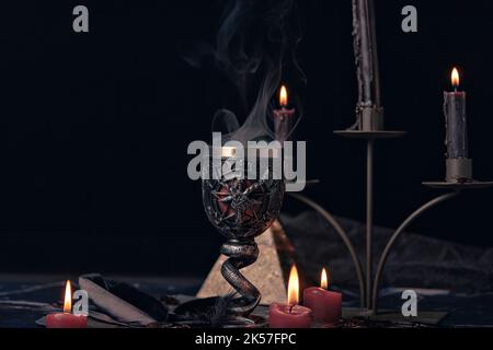 Composizione stregoneria con candele bruciate, gioielli e pentagramma simbolo. Halloween e concetto occulto, rituale magia nera. Foto Stock