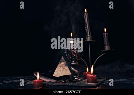 Composizione stregoneria con candele bruciate, gioielli e pentagramma simbolo. Halloween e concetto occulto, rituale magia nera. Foto Stock