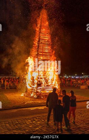 Francia, Eure, la Haye-de-Routot, falò tradizionale di Saint-Clair, una piramide alta 15 metri di legno secco è eretta, sulla piazza del paese, di fronte alla chiesa e i suoi yews millenari. Una messa e una benedizione precedono la combustione del palo, se la croce in cima non brucia, è un buon segno per i 12 mesi a venire, riportando a casa un pezzo di legno charred, chiamato brandon, proteggerà la casa dai fulmini Foto Stock