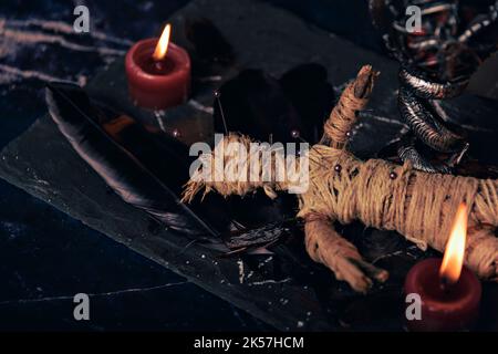 Concetto di Voodoo Magic. Bambola Voodoo costellata di aghi con cuore di straccio trafitto sul pentagramma e intorno a candele brucianti. Spooky o misterioso magico Foto Stock