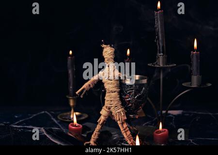 Concetto di Voodoo Magic. Bambola Voodoo costellata di aghi con cuore di straccio trafitto sul pentagramma e intorno a candele brucianti. Spooky o misterioso magico Foto Stock