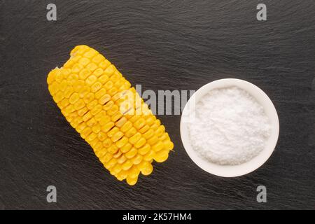 Un fragrante mais bollito con sale su una pietra ardesia, macro, vista dall'alto. Foto Stock