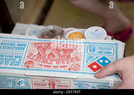 DOMINOES CONSEGNA SCATOLE, RUSTON, LOUISIANA/USA – 15 MAGGIO 2020: Persona afferrare Dominos pizza e scatole di pane che era stato messo in una sedia fuori f Foto Stock