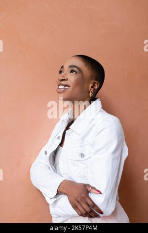 Ritratto di donna afroamericana a capelli corti sorridente mentre si trova vicino al muro, immagine stock Foto Stock