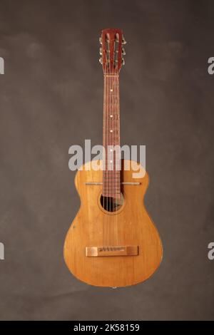 Vecchia chitarra acustica rotta. Lo sfondo è marrone. Primo piano. Foto Stock